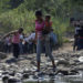 A woman carrying a child walks across the Tachira river on the outskirts of Cucuta, on the Colombian-Venezuelan border, Colombia February 25, 2019. REUTERS/Marco Bello