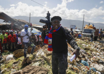 FILE - Barbecue, the leader of the "G9 and Family" gang, stands next to garbage to call attention to the conditions people live in as he leads a march against kidnapping through La Saline neighborhood in Port-au-Prince, Haiti, Friday, Oct. 22, 2021. The group said they were also protesting poverty and for justice in the slaying of President Jovenel Moise. (AP Photo/Odelyn Joseph, File)