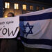 epa10917477 Participants hold an Israeli flag (R) and a placard reading Never again is now (L) in front of the Synagogue at Fraenkelufer in Berlin, Germany, 13 October 2023. As a reaction to the ongoing threat by the militant group Hamas, the German Interior Ministry stated in 'solidarity with Israel', that 'the protection of Jewish and Israeli institutions in Germany was immediately strengthened.'. Activists announced a symbolic protection vigil in front of the Fraenkelufer Synagogue for the evening of 13 October 2023. Thousands of Israelis and Palestinians have died since the militant group Hamas launched an unprecedented attack on Israel from the Gaza Strip on 07 October 2023, leading to Israeli retaliation strikes on the Palestinian enclave. Photo: picture alliance/EPA/CLEMENS BILAN